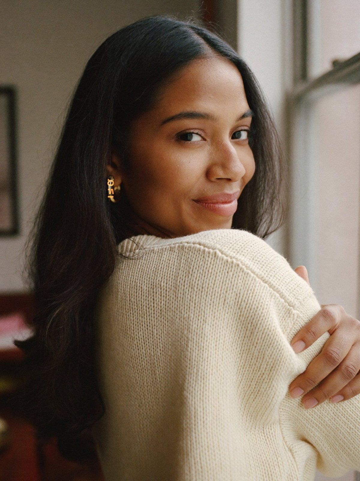 Chin on the shoulder: a woman looks back over her shoulder toward window light